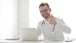© stockbakers - Doctor Showing Thumbs Up Sign While using Laptop in Clinic