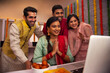 © IndiaPix - Colleagues having video call together on laptop in office during Diwali celebration