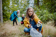 © Halfpoint - Small girl with mother and grandmother picking up waste outoors in forest.