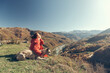 A young woman and a dog on a mountainside overlooking a valley. Autumn, sunny day.