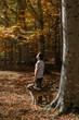 Male traveler walks in the forest with dogs. Very sunny day, orange foliage.
