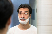 Funny Man With Shaving Foam On His Face Gazing At The Mirror During Shaving 