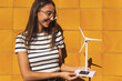 © ADDICTIVE STOCK - Young lady hold small solar powered windmill in countryside