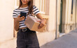 © ADDICTIVE STOCK - Anonymous female courier photographing parcel on street