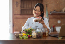 Content Asian Housewife Adding Nuts Into Salad Bowl In Kitchen
