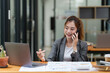 © itchaznong - Young asian business woman smiling and talking on mobile phone