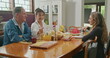 © Marco - Happy couple having breakfast with teenage daughter sitting at kitchen table. The father is talking and the mother is serving juice to the daughter