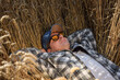 © AlDa.videophoto - Young adult farmer relaxing at agricultural grain field at sunny day. Male worker wearing hat, checkered shirt, sunglasses, lying in ripe wheat field outdoors. Countryside concept. Simple living