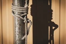 Coarse Rope Wrapped Around Wooden Pole In Vintage Color.Blured Background With A Natural Sunlight