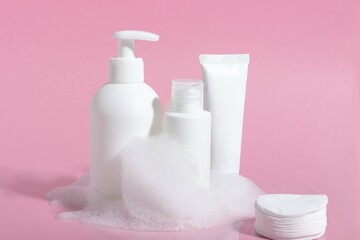 Cosmetics for face, body and hair care. Moisturizer, shampoo or facial cleanser on pink background with foam