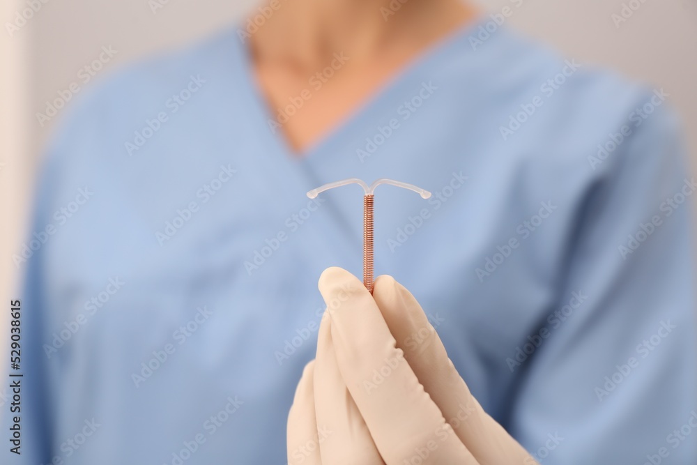Doctor holding T-shaped intrauterine birth control device, closeup ...