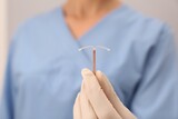 Fototapeta  - Doctor holding T-shaped intrauterine birth control device, closeup