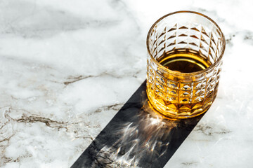 photography of scotch whisky glass in a marble table with light and shadow