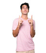 Hesitant young man pointing up with his finger