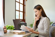 © bongkarn - Attractive and relaxed young Asian woman reading a book at her office desk.