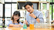 © bongkarn - A cute little Asian girl studying science at home with her private tutor.