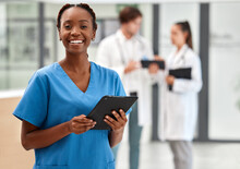 Portrait Of Happy Woman Doctor Working On A Digital Tablet And Smile While Working At A Hospital. Black Female Nurse Doing Medical And Healthcare Research On The Internet Or Online At Work At Clinic