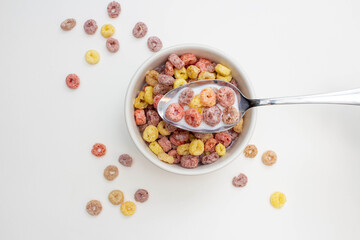 Wall Mural - Breakfast cereal concept, Colorful ring cereals with milk in bowl and falling on white background