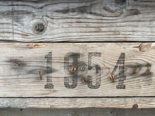 On A Weathered Wooden Board Is Printed In Black Paint The Number 1954