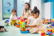© PoppyPix - Nursery school. Toddlers and their teacher playing with colorful plastic playhouses, cars and boats. Imagination, creativity, fine motor and gross motor skills development. High quality photo