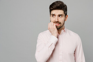 Wall Mural - Young minded worried sad upset caucasian man 20s wear basic white shirt look aside on workspace copy space mock up area biting nails isolated on plain grey background studio People lifestyle concept.