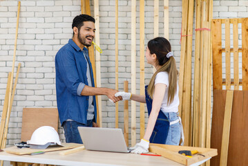 Wall Mural - Asian Indian professional cheerful bearded male and female engineer architect foreman labor worker standing shaking hands together show teamwork making deal done in interior home construction site