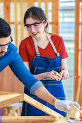 Wall Mural - Asian professional female engineer architect foreman labor worker wears safety goggles glasses and jeans apron standing listening to colleague holding writing note on clipboard in construction site