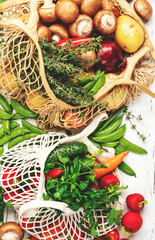 Wall Mural - Healthy food selection: mushrooms, beans, tomatoes, avocados, and herbs. Reusable shopping textile bags full of organic spring vegetables from local farmers market.