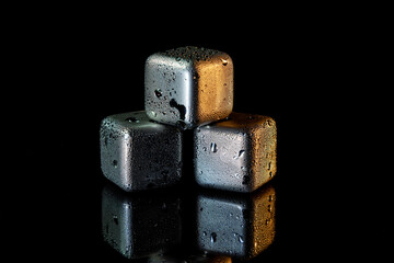 Wall Mural - Stainless steel cubes simulating ice for cooling drinks on a black surface with a reflection.