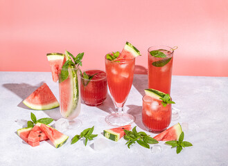 Wall Mural - Different elegant glasses with watermelon cocktail. Splash, splatter, water drops on the pink background