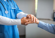 © Prostock-studio - Cropped millennial male doctor in uniform calming, shaking hand with old woman patient in clinic