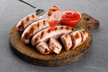 Wall Mural - Grilled German, Munich, Bavarian, sausages with ketchup and rosemary on gray background. Fork with sausage.