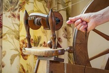 Action Detail Of Hands Working Old Fashioned Wool Spinning Wheel. Vintage Tailoring Equipment Concept. Traditional Devices.