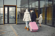 Mother, father and daughter with luggage going to airport terminal