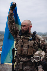 A military man holds the flag of Ukraine. Portrait of the defender of Ukraine.