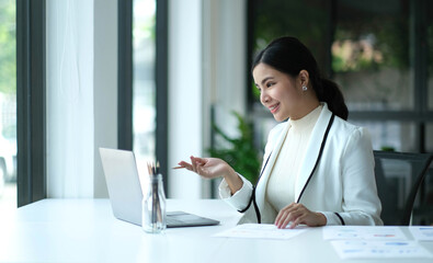 Charming asian businesswoman sitting working on laptop in office.