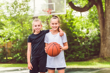 two girl child in sportswear playing basketball game