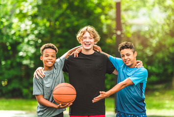 Wall Mural - three teens friends in sportswear playing basketball game