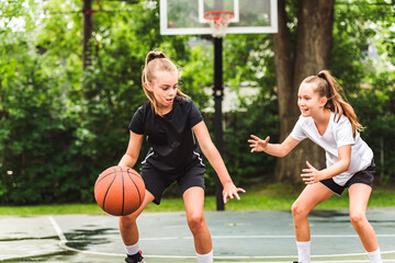 two girl child in sportswear playing basketball game