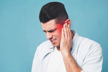 Wall Mural - Man suffering from ear pain on light blue background