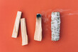 Smoldering incense. White sage and palo santo sticks in a row over orange red background. Bundle for meditation and room fumigation. Selective focus. Flat lay style