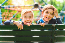 Portrait Of A Little Boy With Down Syndrome Sit On A Bench With His Brother