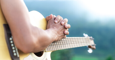 Wall Mural - Man praying on acoustic guitar, Close up and focus at hand.