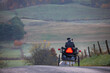 Amish woman riding her horse and buggy cresting a hill in the countryside of Holmes County, Ohio