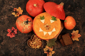 Pumpkin and zucchini cream soup with roasted seeds and toast in hollowed out pumpkin, traditional autumn halloween vegan food, baked in oven, healthy natural breakfast, 