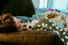 Boy And Dog Sleeping On Sofa At Home