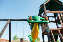 Low Angle View Of Girl Playing On Outdoor Play Equipment Against Clear Sky
