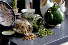 Close-up Of Herbs Fallen From Jars On Table