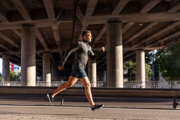 Wall Mural - fitness, sport and healthy lifestyle concept - young man running outdoors under bridge