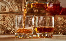 Close-up Of Whiskey Being Poured Into Glass On Table